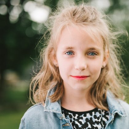 A young girl with blue eyes and blonde hair smiles